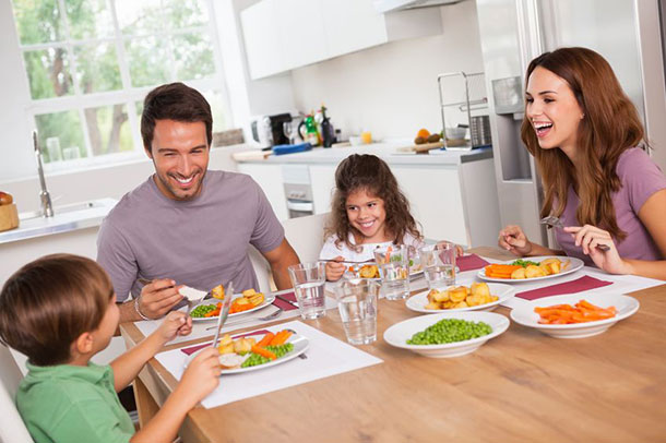 Une famille est assise à la table et propose une variété de légumes cuits.