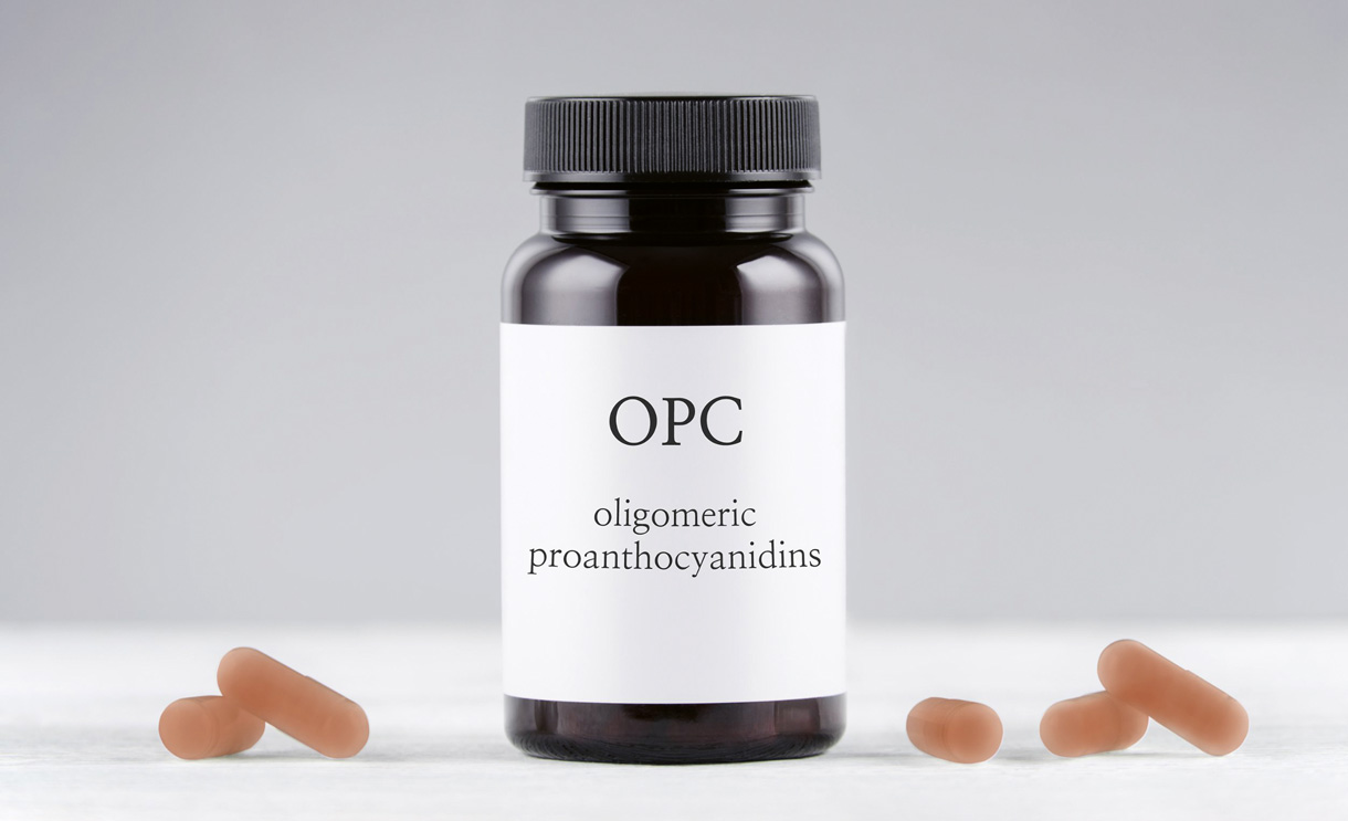 Das Bild stellt ein fiktifes Arzneimittel mit OPC dar. In der mitte steht ein dunkles Fläschen mit einer weissen Etikette und der Aufschrift \" OPC, Oligomere Proanthocyanidine\". Links und rechts daneben liegen noch Kapseln.