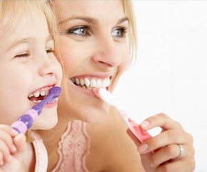 Mutter und Tochter putzen sich mit Freude die Zähne.