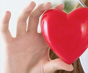 Eine Hand hält ein rotes Herz ins Bild.
